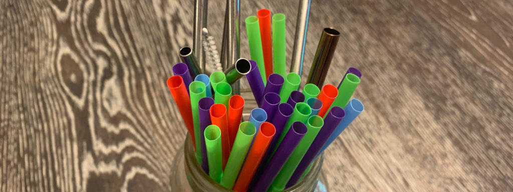 Mason jar full of colourful straws on brown wood table