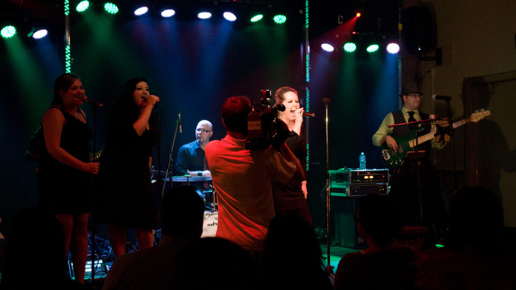 Amanda Kind singing on stage with band and back up singers