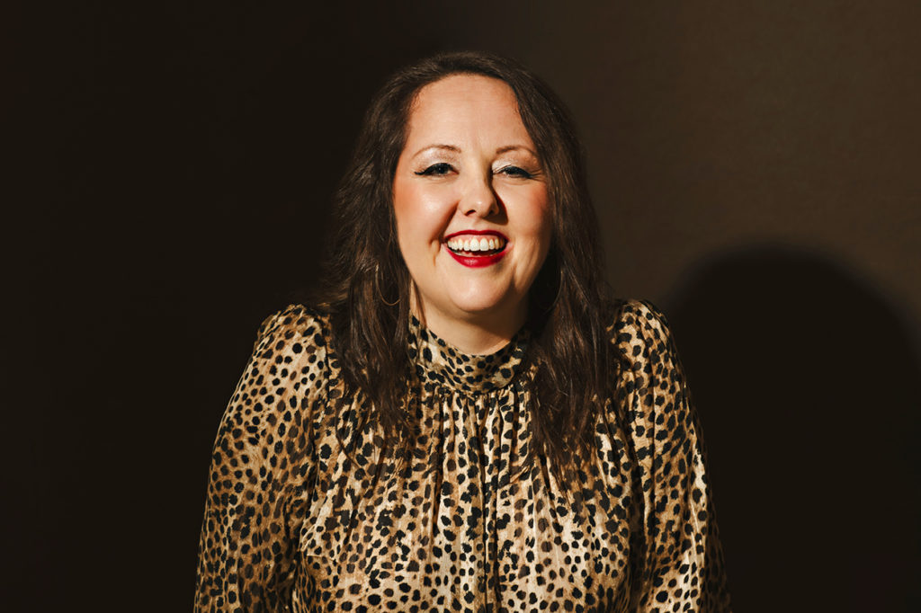 Amanda Kind in leopard blouse on dark background